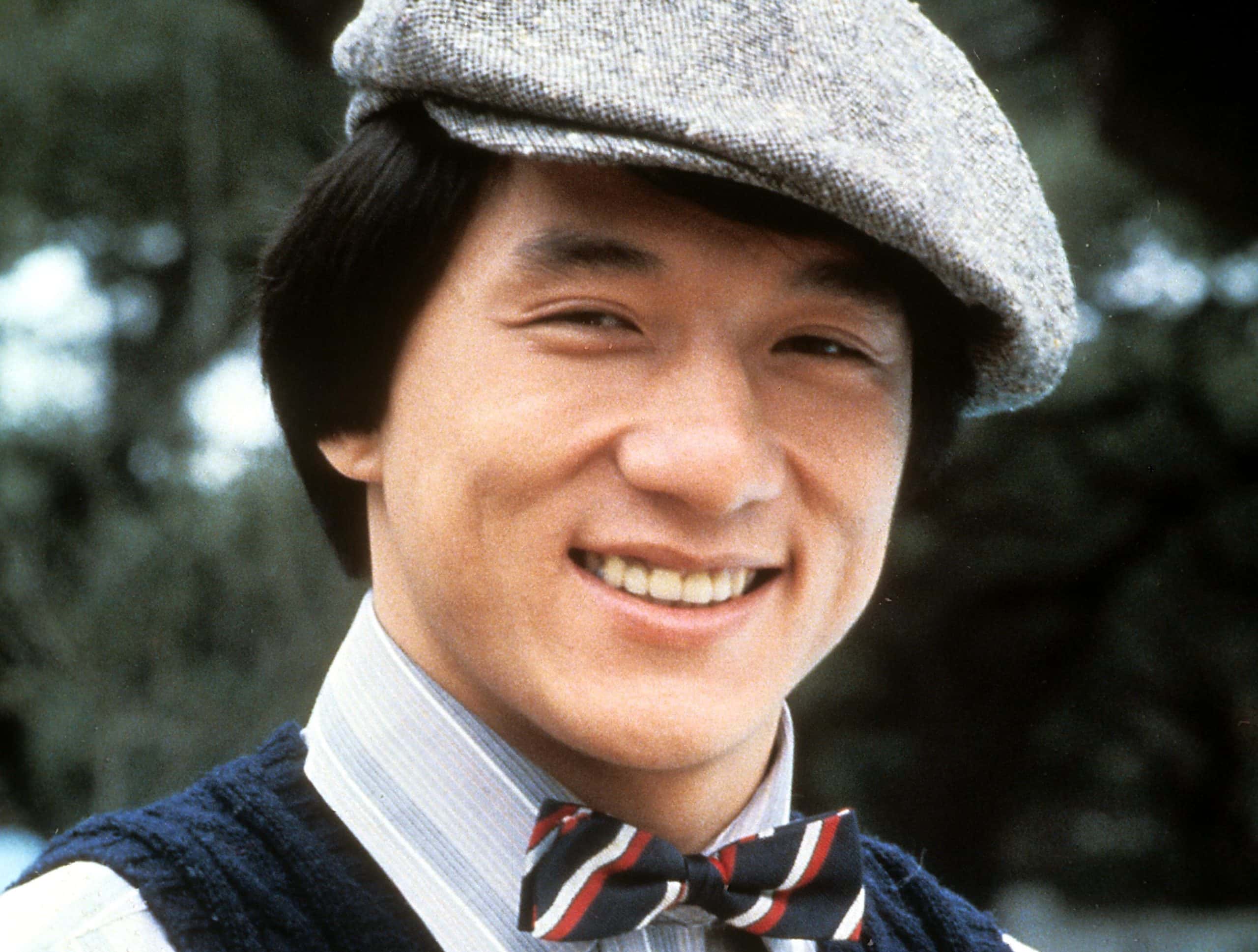 Portrait Photo of the actor Jackie Chan wearing a shirt, tie and a hat